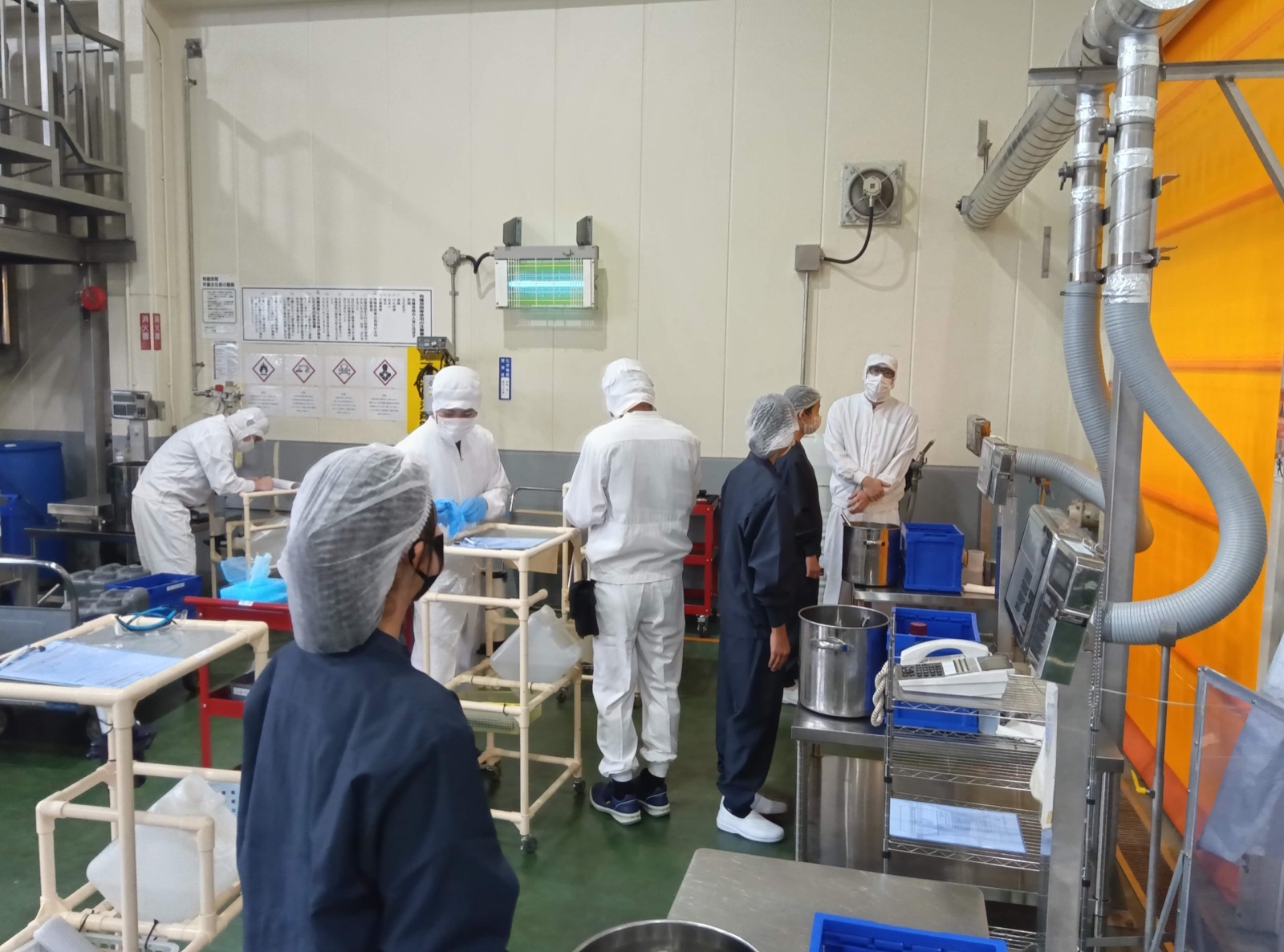 工場内で作業の説明を受ける見学者