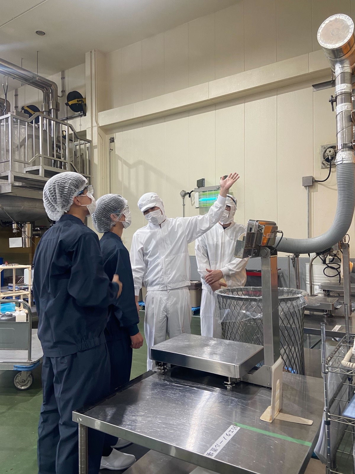 製造設備の説明を聞く見学者